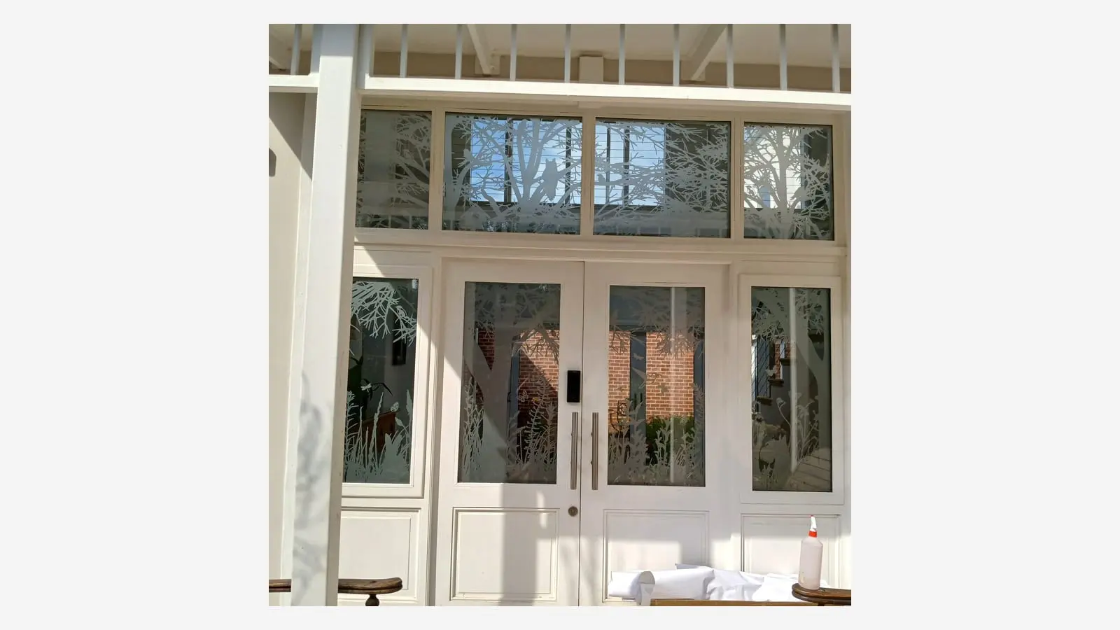 Frosted vinyl with tree, branch and wildlife details applied to glass entrance doors and surrounding panels