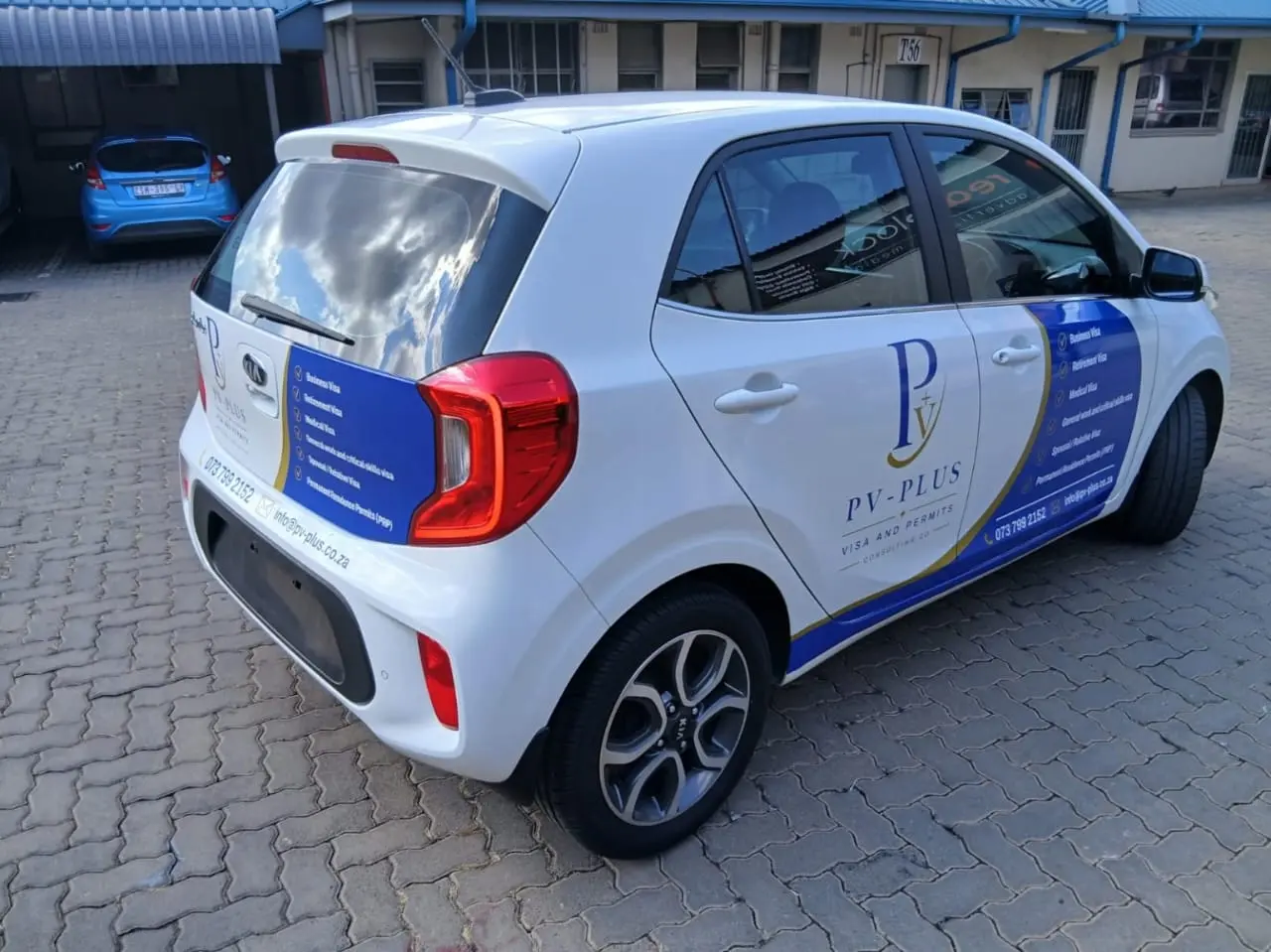 Rear three-quarter view of PV Plus partial vehicle branding on a Kia Picanto