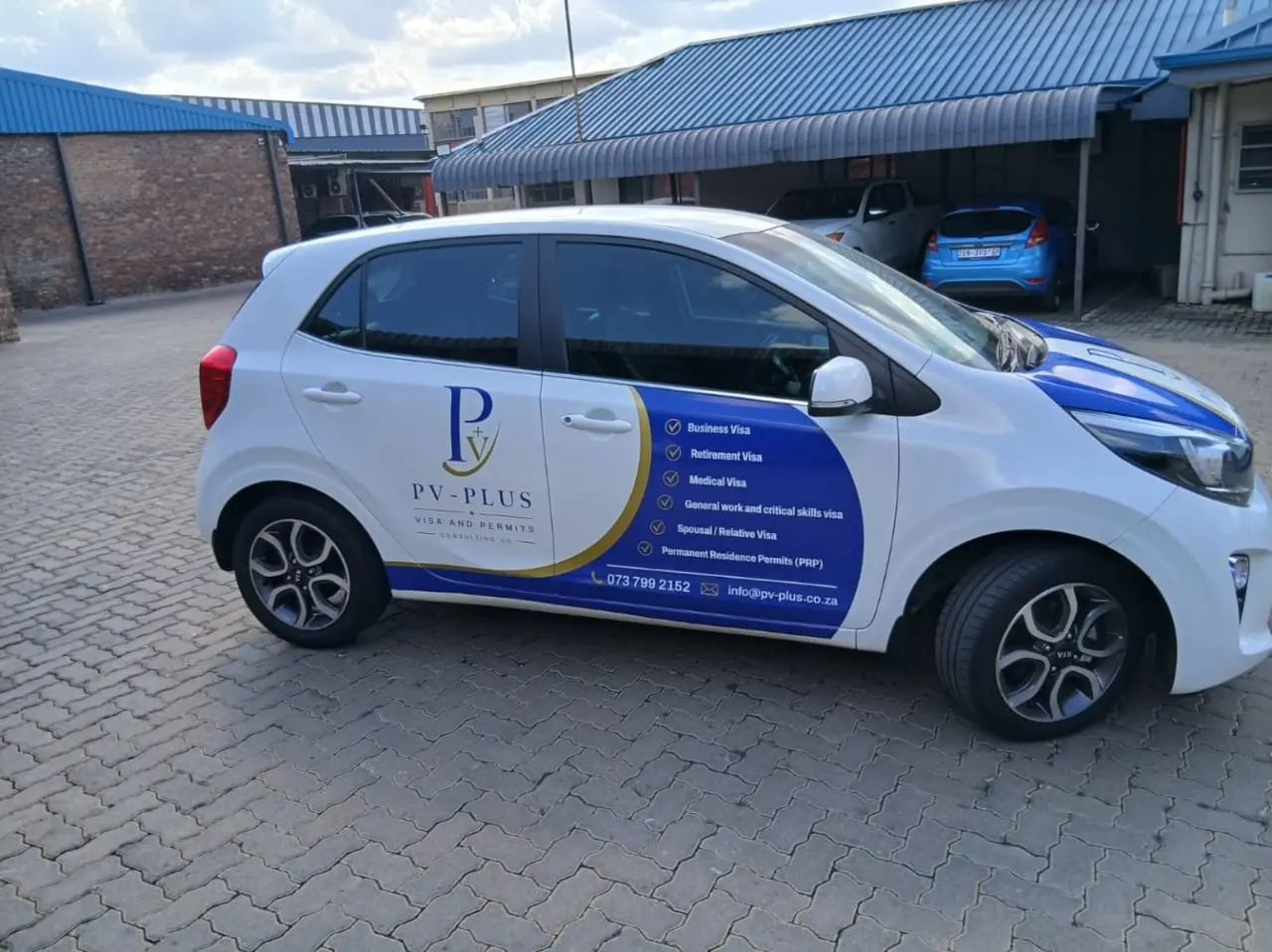 Side view of PV Plus partial vehicle branding and vinyl lettering on a white Kia Picanto