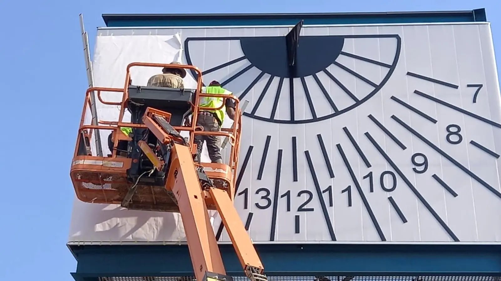 Redblock installation team applying the large-format Cubed sundial graphic at height